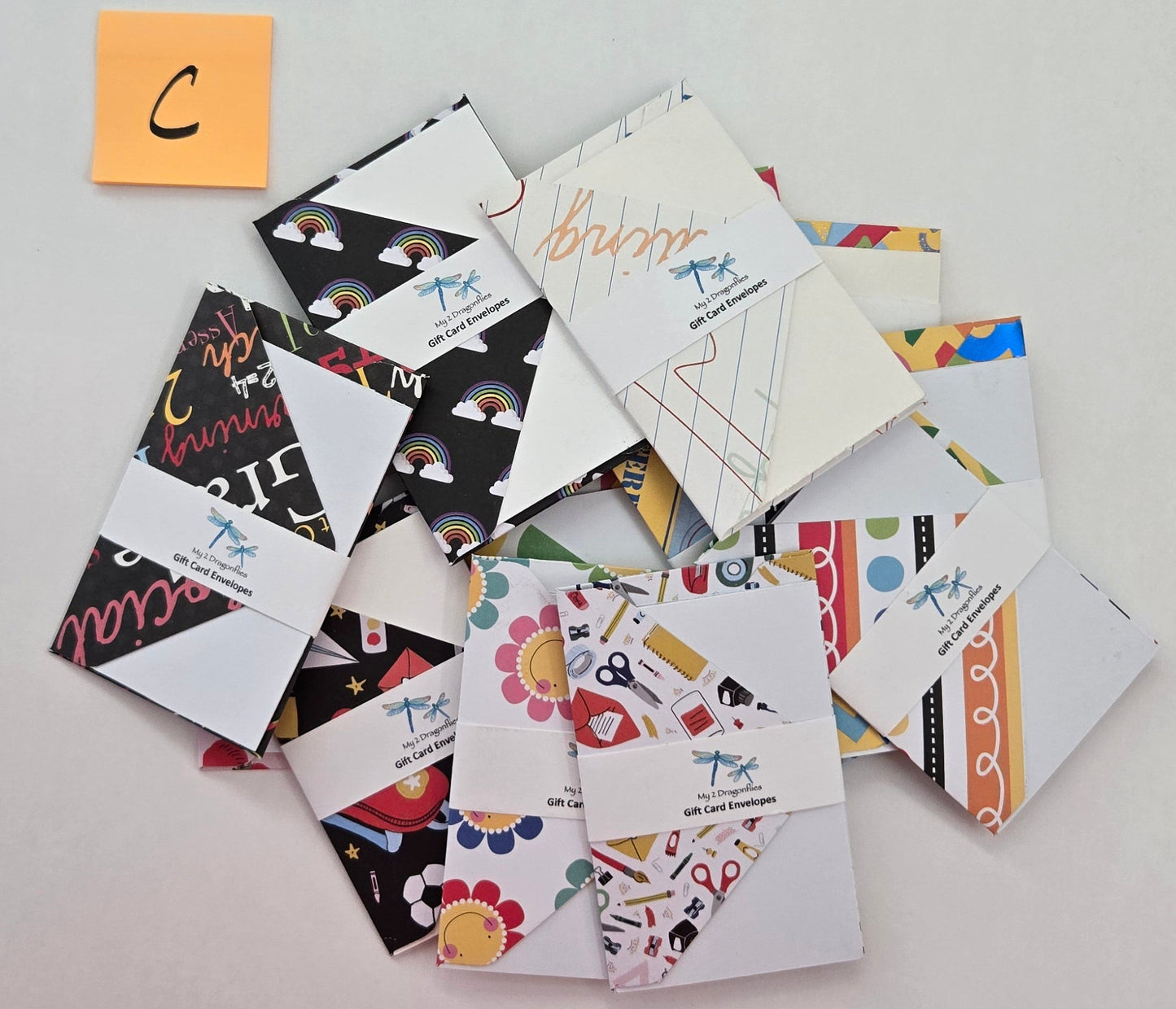 Collection of small envelopes with various designs on a light gray surface.