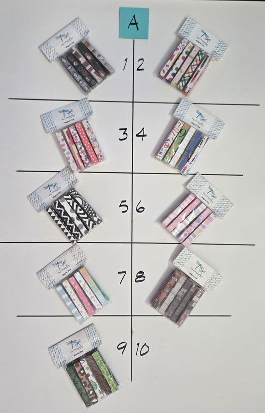 Assorted patterned magnet clips arranged in a grid on a white sheet of paper.