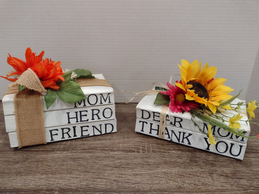 Two decorative books with floral arrangements on a surface.